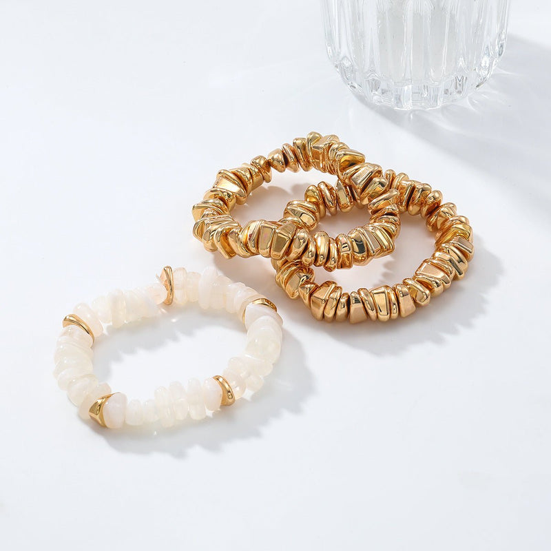 Trio de bracelets femme, deux dorés métallisés en forme de perles irrégulières et un blanc nacré opaque, style chic soirée.
