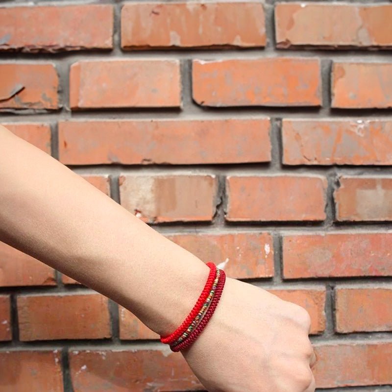 Trio de bracelets tibétains rouges en fil ciré, style minimaliste et élégant, porté au poignet.