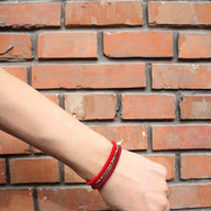 Trio de bracelets tibétains rouges en fil ciré, style minimaliste et élégant, porté au poignet.