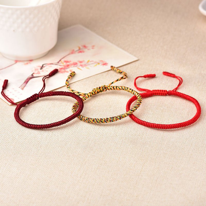 Trio de bracelets tibétains en fil rouge ciré, un modèle rouge avec un tissage simple, un autre rouge bordeaux texturé et un .