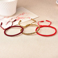 Trio de bracelets tibétains en fil rouge ciré, un modèle rouge avec un tissage simple, un autre rouge bordeaux texturé et un .
