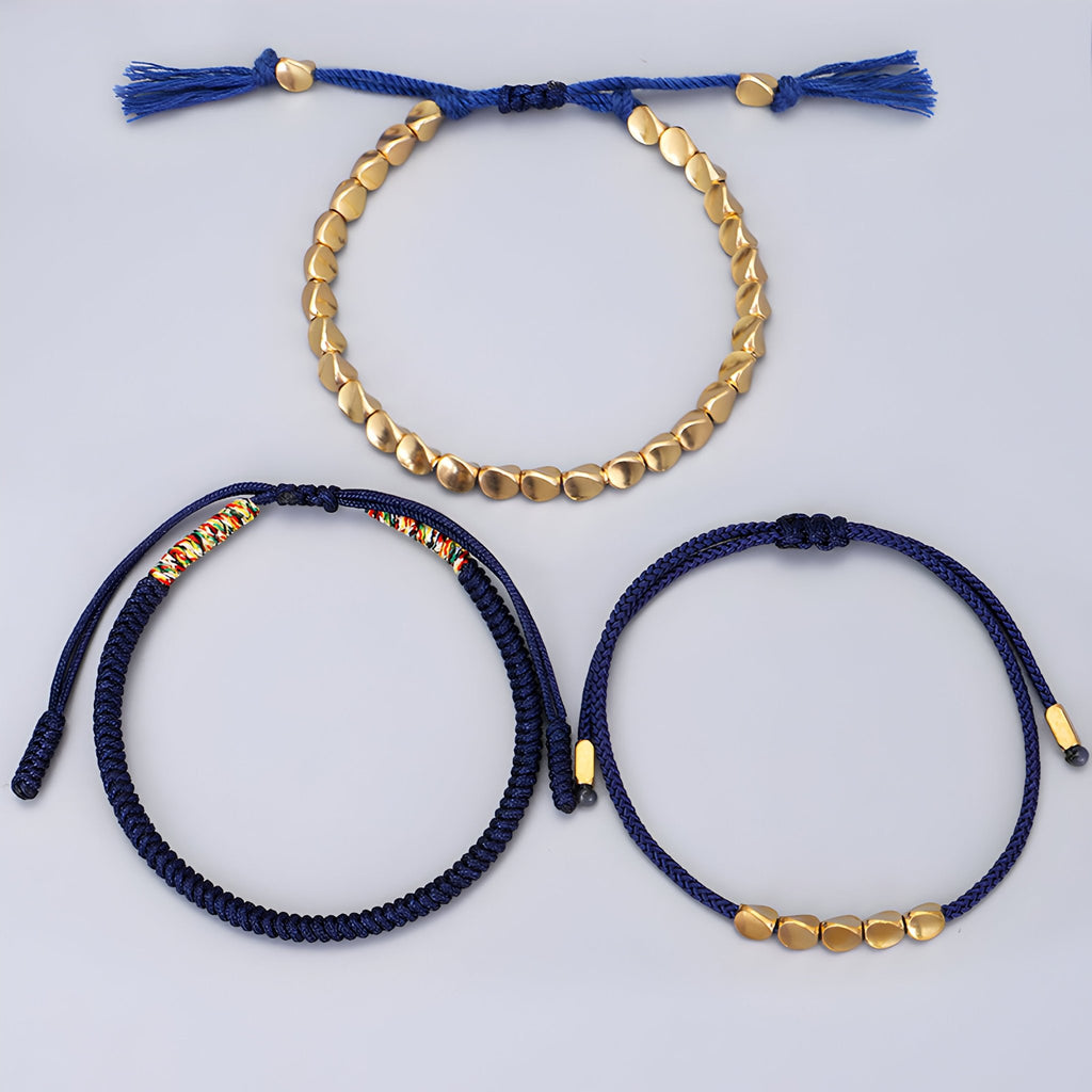 Trio de bracelets tibétains bleus en corde avec perles et pièces en cuivre doré.