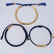 Trio de bracelets tibétains bleus en corde avec perles et pièces en cuivre doré.