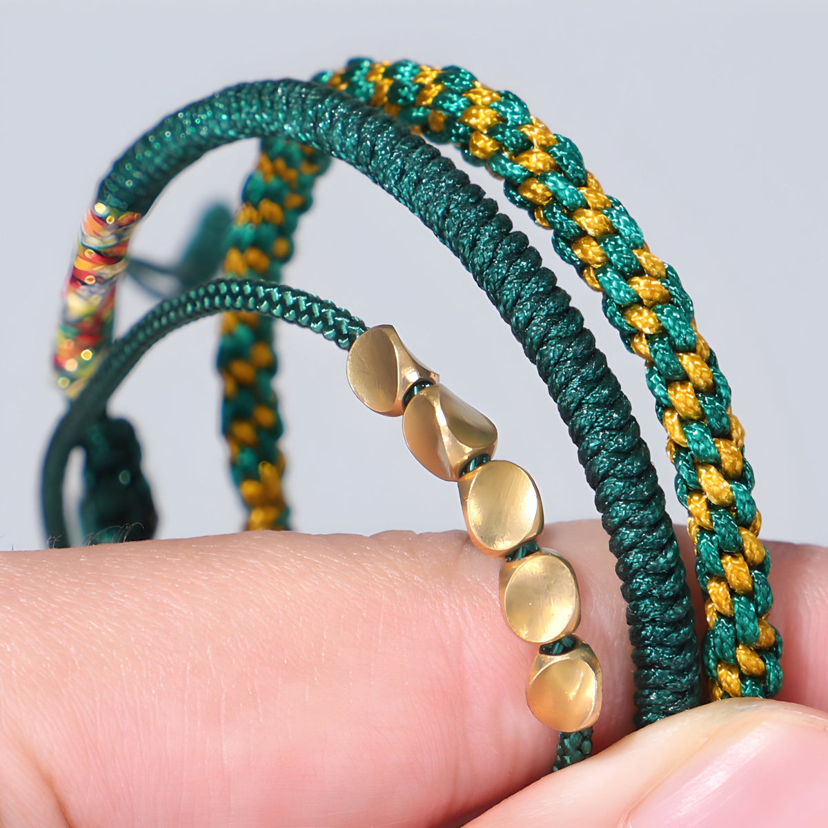 Trio de bracelets tibétains verts en corde tressée et perles en cuivre doré pour femme.