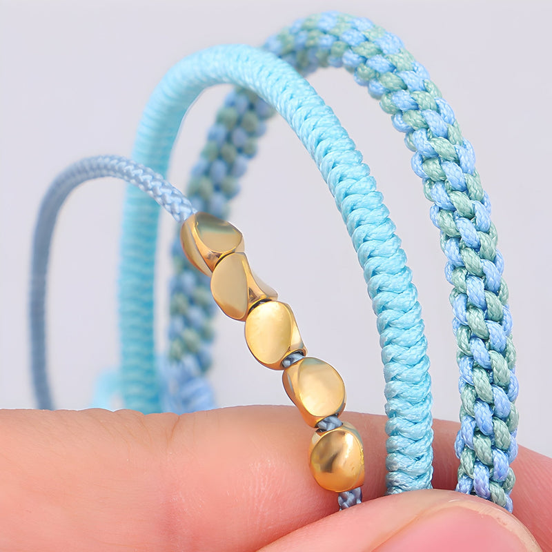 Trio de bracelets tibétains bleus en corde tressée avec perles en cuivre doré, style porte-bonheur.