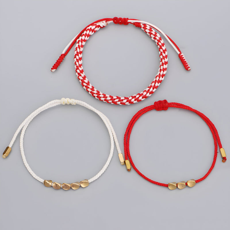 Trio de bracelets tibétains en corde rouge, blanche et noire avec perles en cuivre doré.
