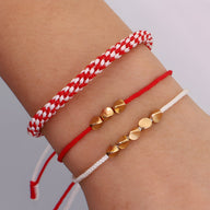 Trio de bracelets tibétains en corde rouge, blanc et cuivre à motifs cœurs et ronds.