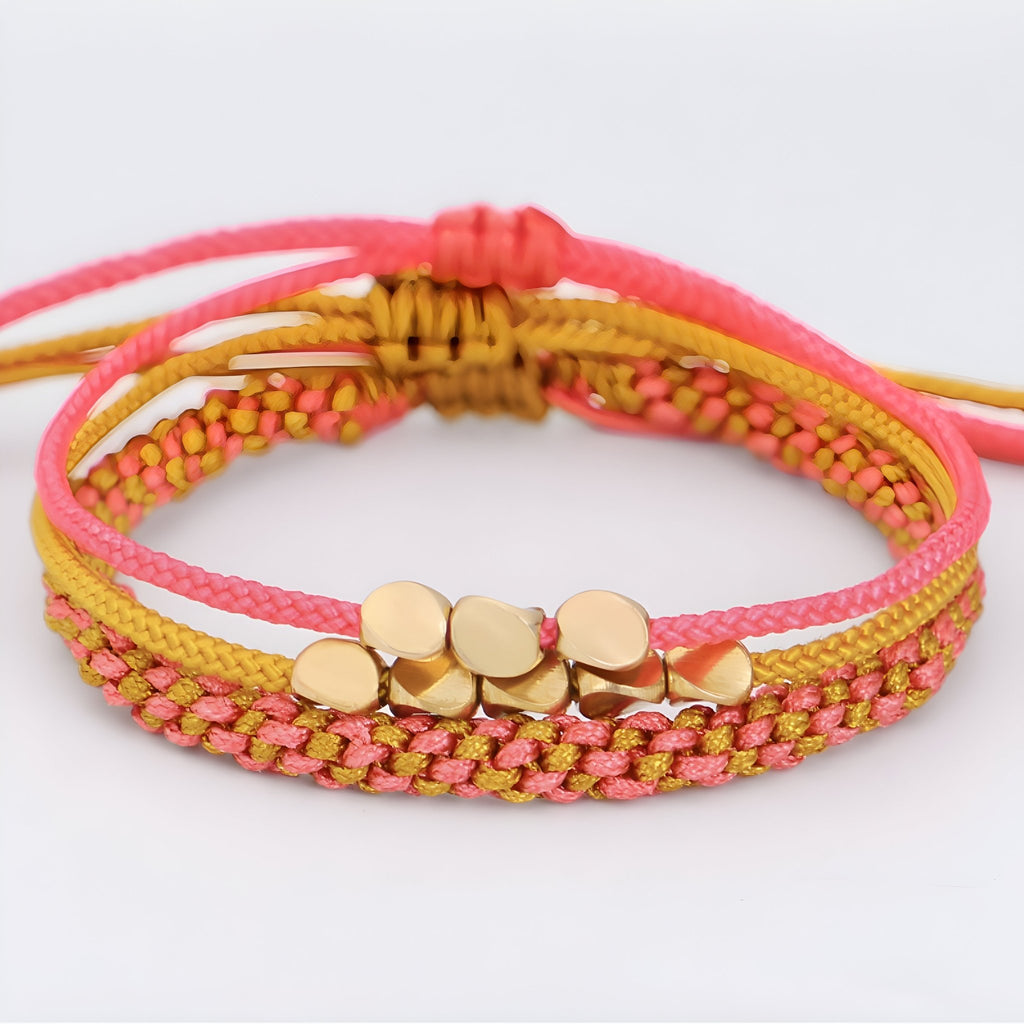 Trio de bracelets tibétains en corde rose et jaune avec perles en cuivre doré.