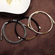 Trio de bracelets tibétains en corde noir et blanc, beige et blanc, avec détails en cuivre doré.