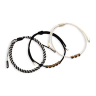 Trio de bracelets tibétains en corde noire, blanche et cuivre avec détails tressés et perles cuivrées.