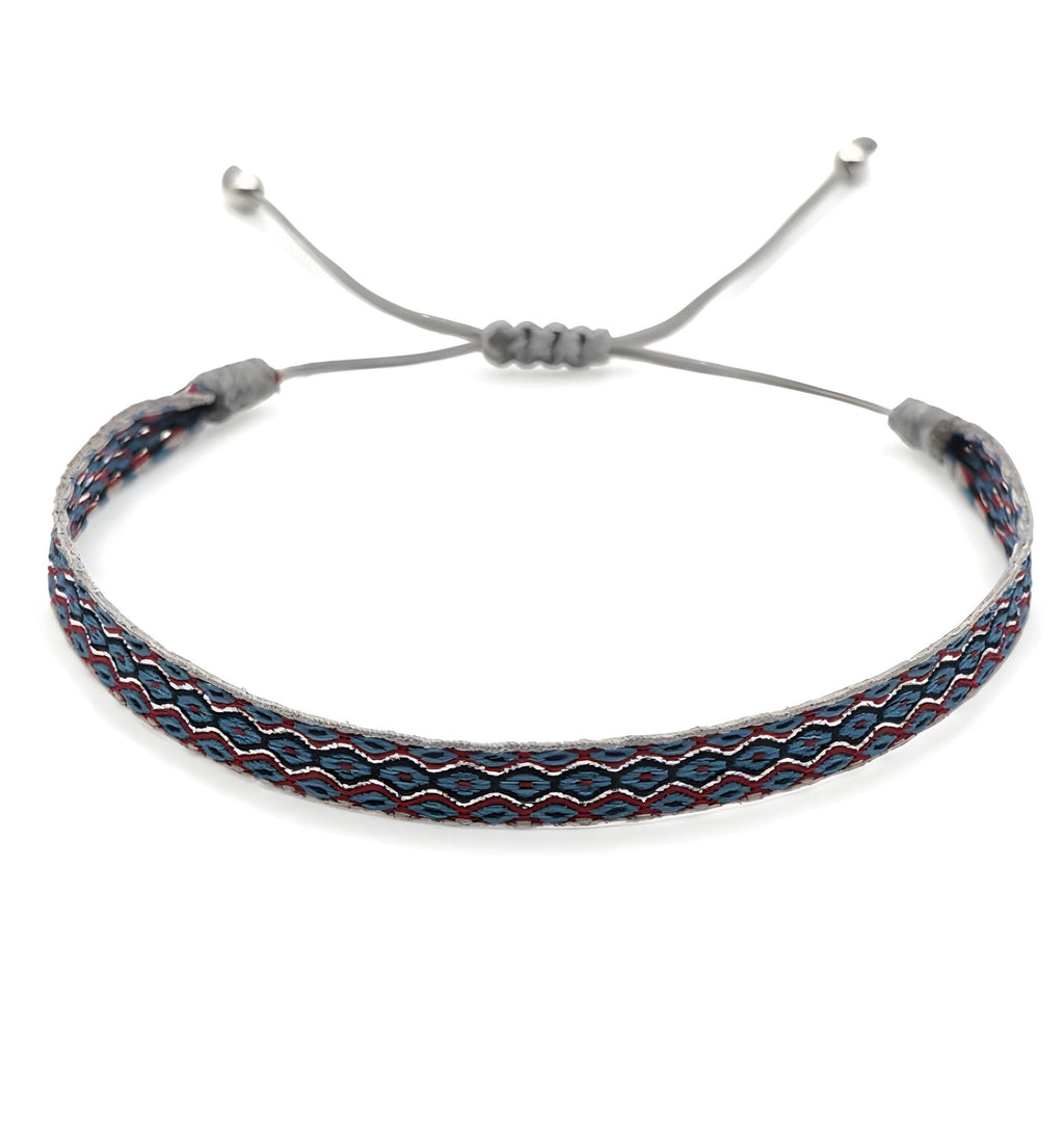 Bracelet tibétain tissu bleu avec motifs rouges et blancs, ajustable avec cordon gris et perles en argent.