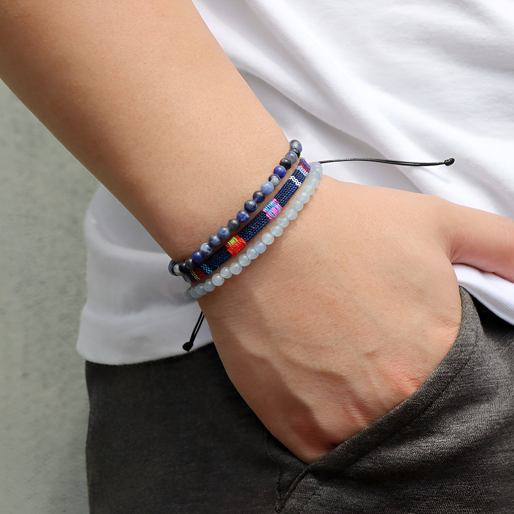 Trio de bracelets tibétains bleus en calcédoine et perles multicolores sur poignet masculin.