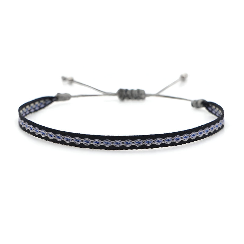 Bracelet tibétain bleu et noir en coton tressé avec fermoir coulissant gris.