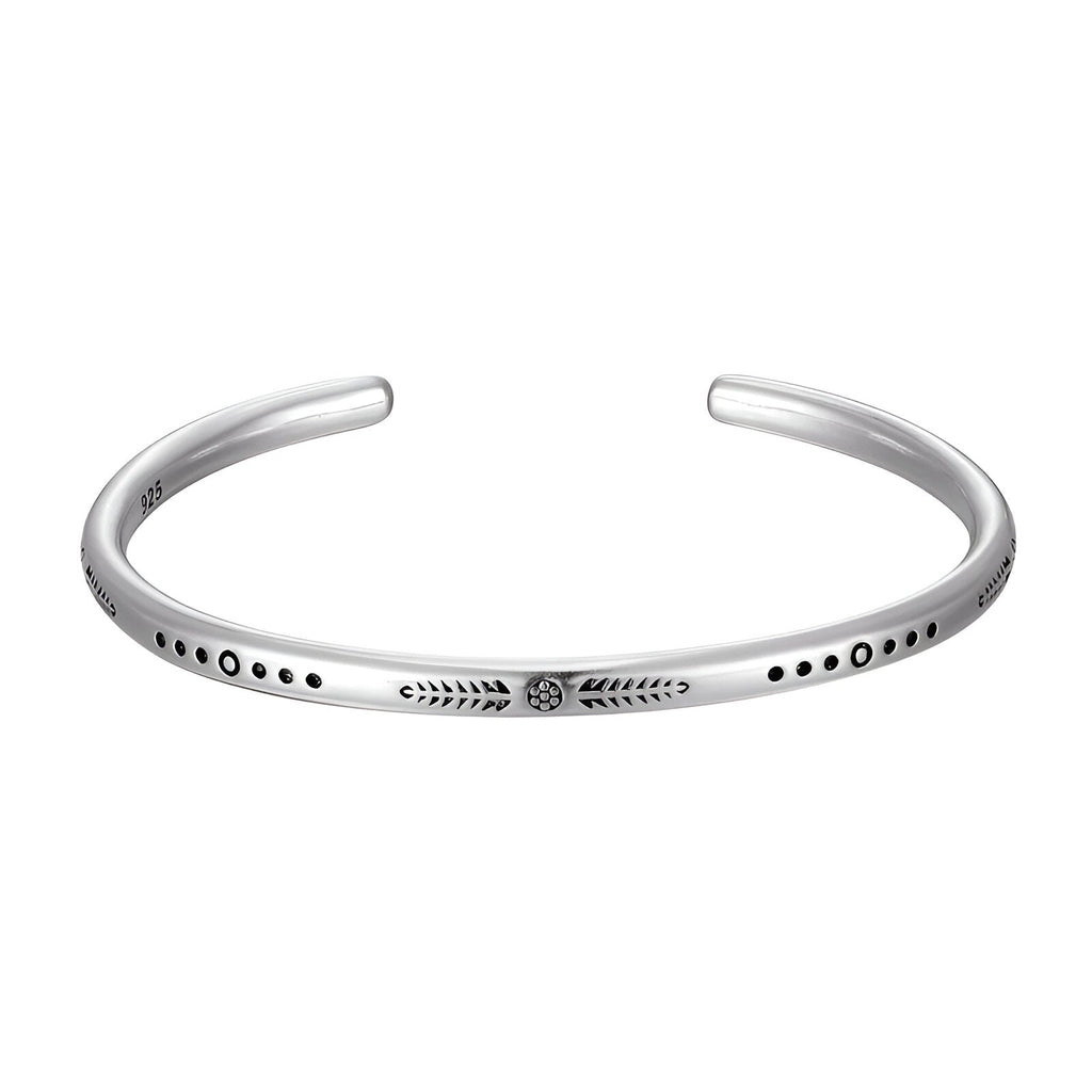Bracelet jonc en argent avec motif gravé et détails en pointillés noirs, style minimaliste.