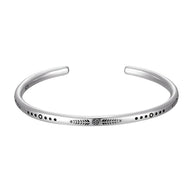 Bracelet jonc en argent avec motif gravé et détails en pointillés noirs, style minimaliste.