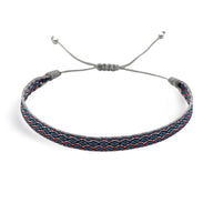 Bracelet tibétain Patricio en coton bleu et rouge avec motifs géométriques et fermoir coulissant gris.