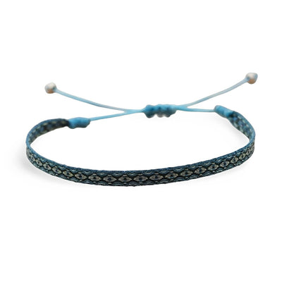 Bracelet tibétain bleu et blanc en fil tressé avec motifs ethniques et fermoir coulissant ajustable.