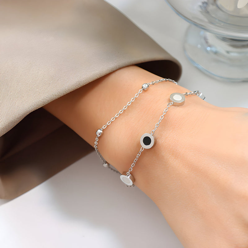 Bracelet ajustable en titane doré avec trois motifs colorés ronds sur chaîne fine.