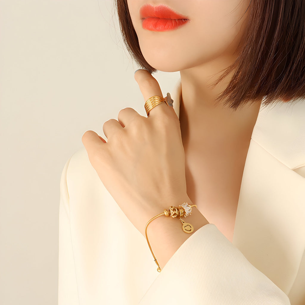 Bracelet ajustable en titane doré avec motif cœur et pierres de zircon sur poignet féminin.