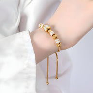 Bracelet ajustable en titane plaqué or avec perles et cristaux scintillants portée au poignet.