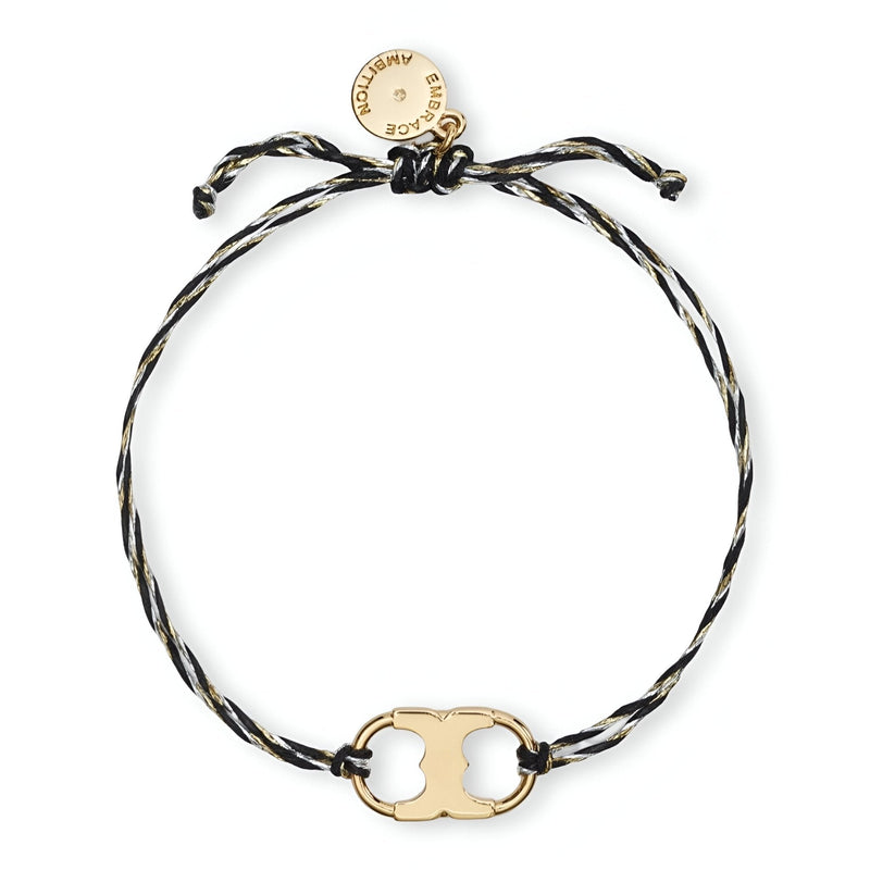 Bracelet cordon noir et blanc avec plaque dorée minimaliste et fermoir coulissant.