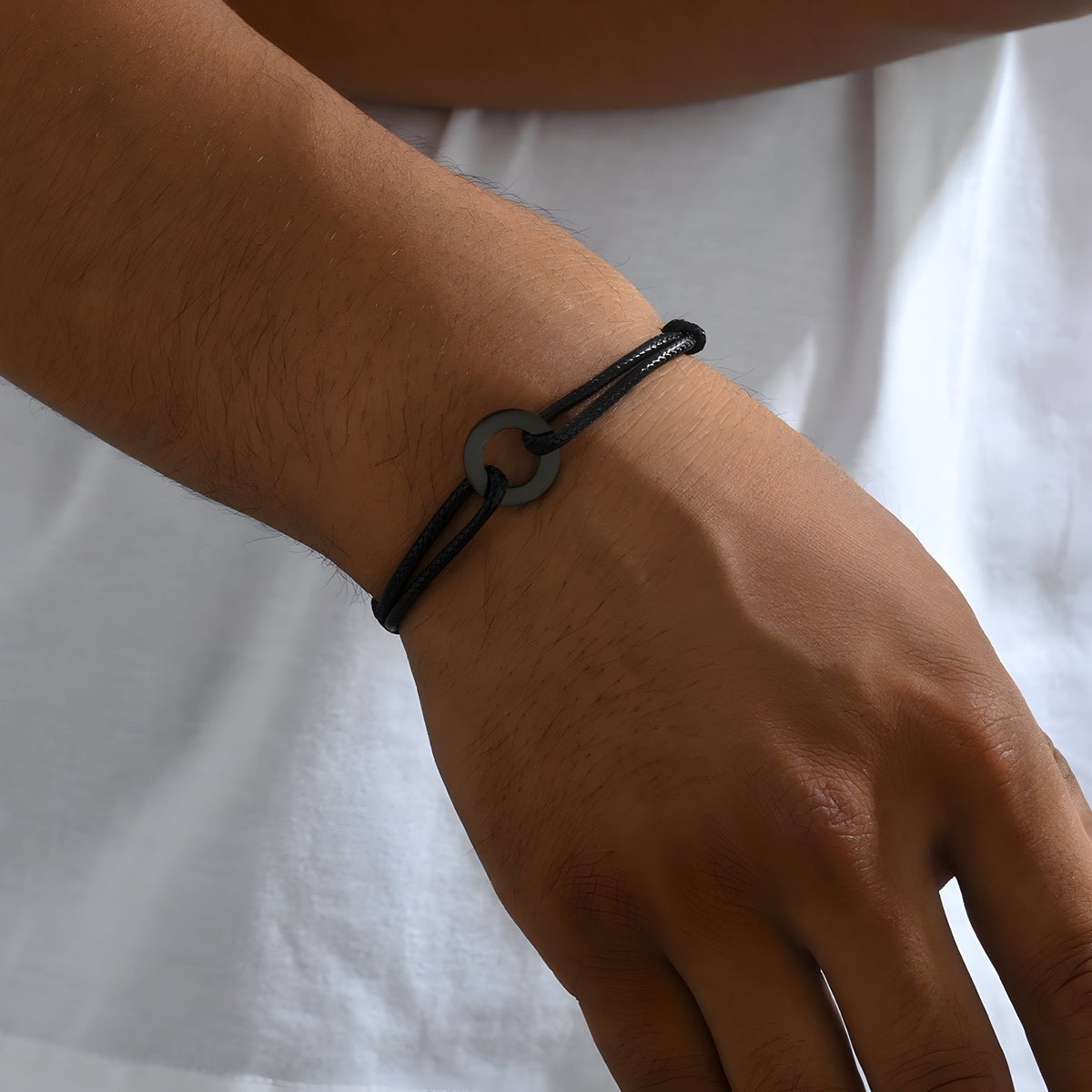 Bracelet cordon noir pour homme avec charm arrondi mat élégamment tressé.