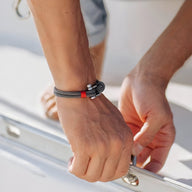 Bracelet cordon gris avec mousqueton argenté, style marin ajustable sur poignet homme.