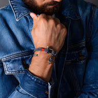 Bracelet cordon orange avec mousqueton argenté porté au poignet homme, style décontracté.