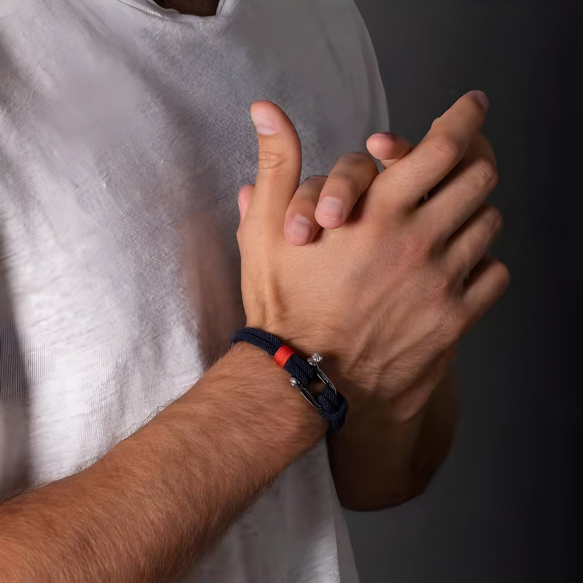 Bracelet cordon marine avec mousqueton argenté et détail rouge porté au poignet homme.