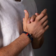 Bracelet cordon marine avec mousqueton argenté et détail rouge porté au poignet homme.