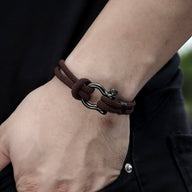 Bracelet cordon marron avec mousqueton en métal argenté, style masculin ajusté au poignet.