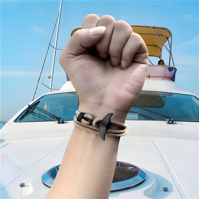 Bracelet cordon noir avec pendant queue de baleine en bois sur poignet masculin, style marin.