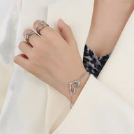 Bracelet délicat en titane plaqué argent avec pendentif coeur ajouré porté au poignet.