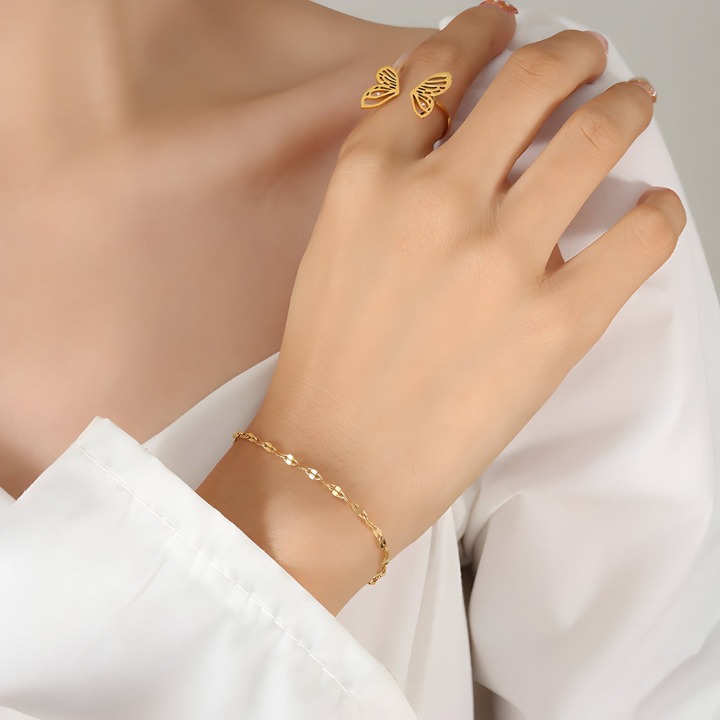 Bracelet fin en titane plaqué or avec petits cœurs pendants, style délicat et féminin.