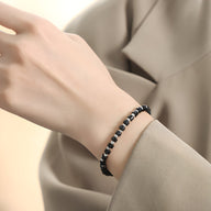 Bracelet élégant en acier inoxydable noir avec perles rondes, modèle Lilianne, porté au poignet féminin.