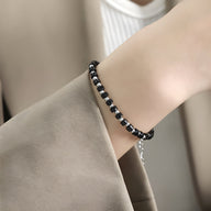 Bracelet Lilianne en acier inoxydable avec perles noires et argentées sur poignet femme.