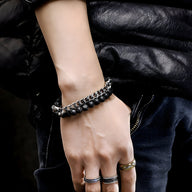 Bracelet en acier inoxydable avec pierres volcaniques noires et doubles têtes de mort argentées.