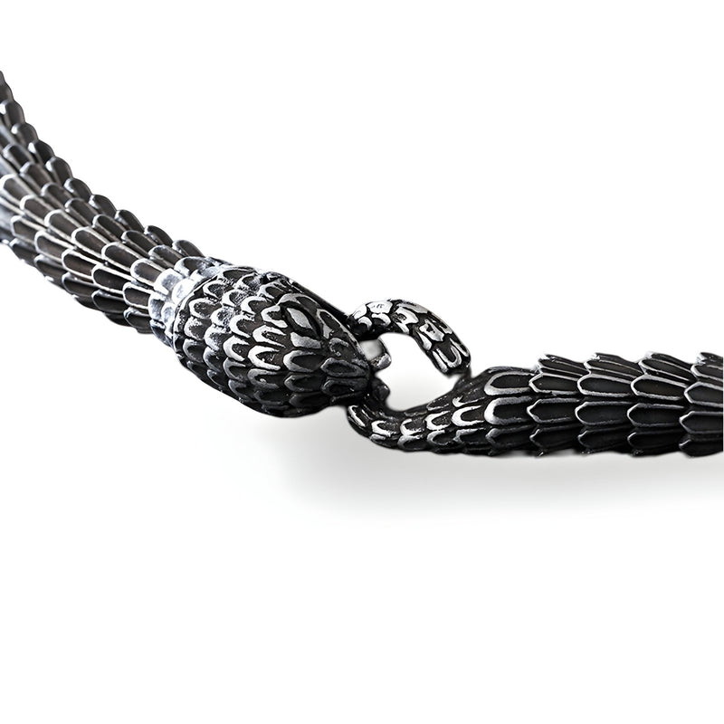 Bracelet serpent en acier inoxydable noir avec détail texturé écailles et fermoir anneau circulaire.
