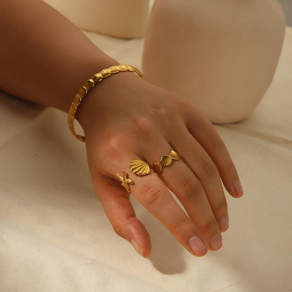 Bracelet jonc en acier inoxydable plaqué or avec motif texturé porté au poignet féminin.