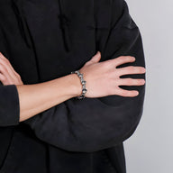 Bracelet en acier inoxydable argenté avec charms gants de boxe porté sur poignet masculin.