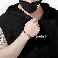 Bracelet en acier inoxydable gris à maillons épais porté sur poignet masculin.