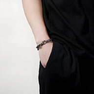 Bracelet chaîne en acier inoxydable gris porté sur poignet masculin avec tenue noire élégante.