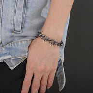 Bracelet pour homme en acier inoxydable anthracite style clous tordus porté au poignet.