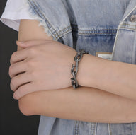 Bracelet homme en acier inox anthracite avec maillons aspect clous tordus portée sur poignet.