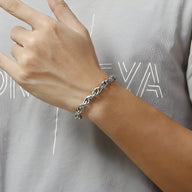 Bracelet homme en acier inoxydable argenté, maille forçat classique, porté au poignet.