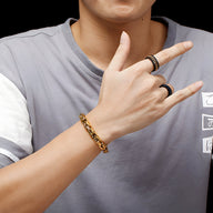 Bracelet maille cubaine en acier inoxydable doré porté au poignet d'homme, finition brillante.