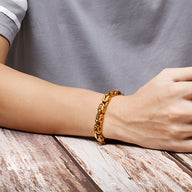 Bracelet homme en acier inoxydable or à maille cubaine épaisse sur poignet.