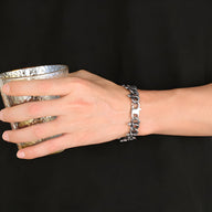 Bracelet argenté en acier inoxydable pour homme avec entrelacement de serpents sur poignet.