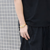 Bracelet jonc pour homme en acier inoxydable couleur or avec finition lisse porté au poignet.