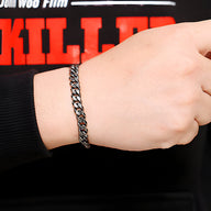 Bracelet homme en acier inoxydable gris à maille cubaine portée au poignet.